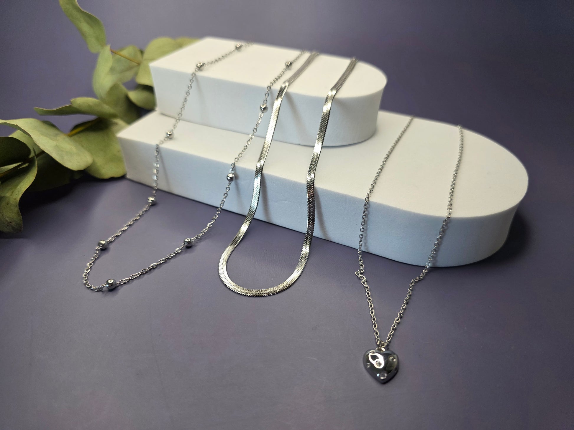 The Siren Serenity set displayed in a foam stellation. This waterproof silver-toned stack features three distinct stainless steel necklaces - My Silver Lining.