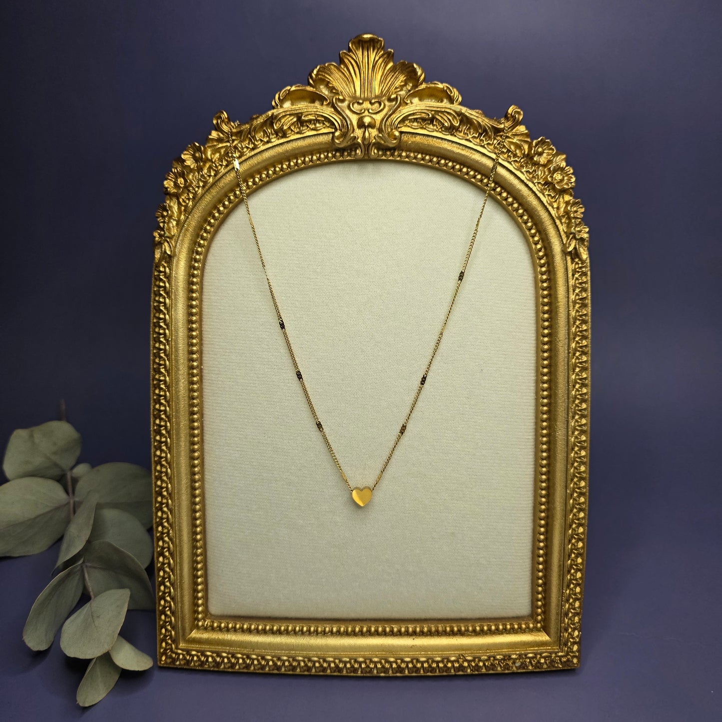 Optimized artistic shot of the gold Tiny Heart Necklace in a vintage-style frame, highlighting the polished heart detail — My Silver Lining.