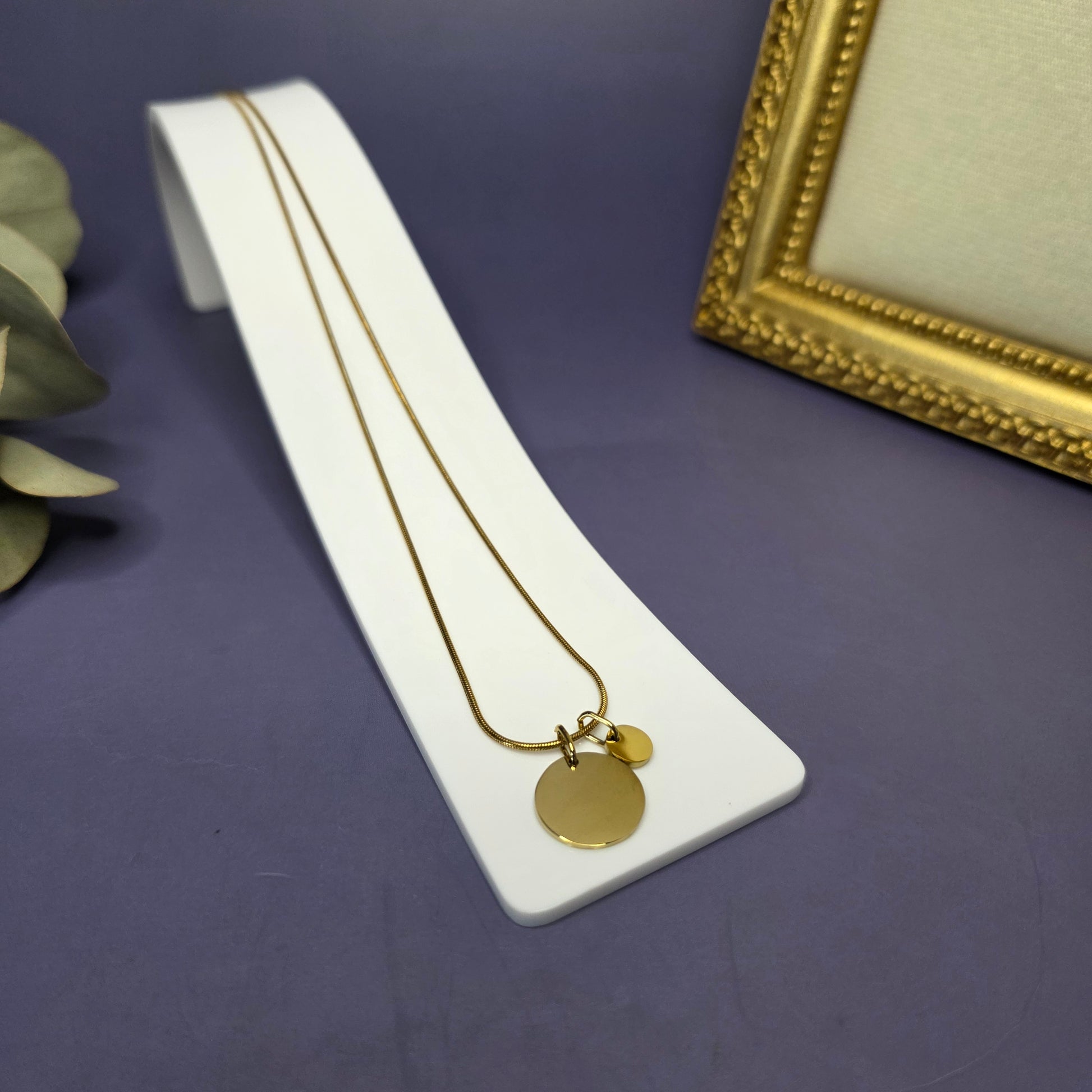 Angled view of the Golden Mamma Bear necklace on a white display stand, featuring one smaller initial pendants — My Silver Lining.
