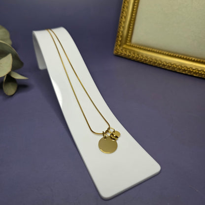 Angled view of the Golden Mamma Bear necklace on a white display stand, featuring two smaller initial pendants — My Silver Lining.