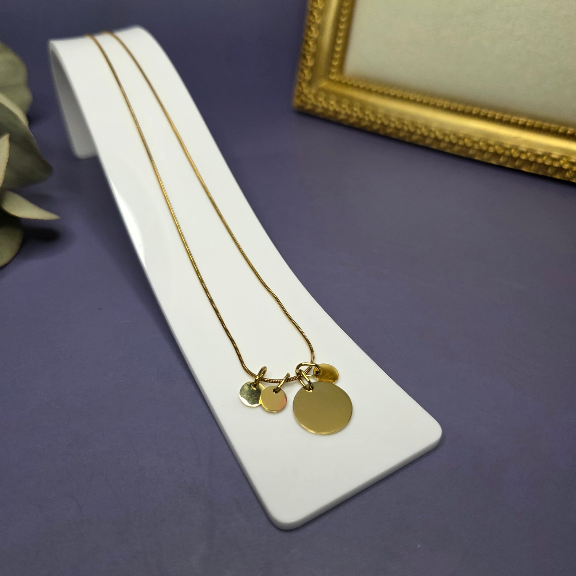 Angled view of the Golden Mamma Bear necklace on a white display stand, featuring three smaller initial pendants — My Silver Lining.
