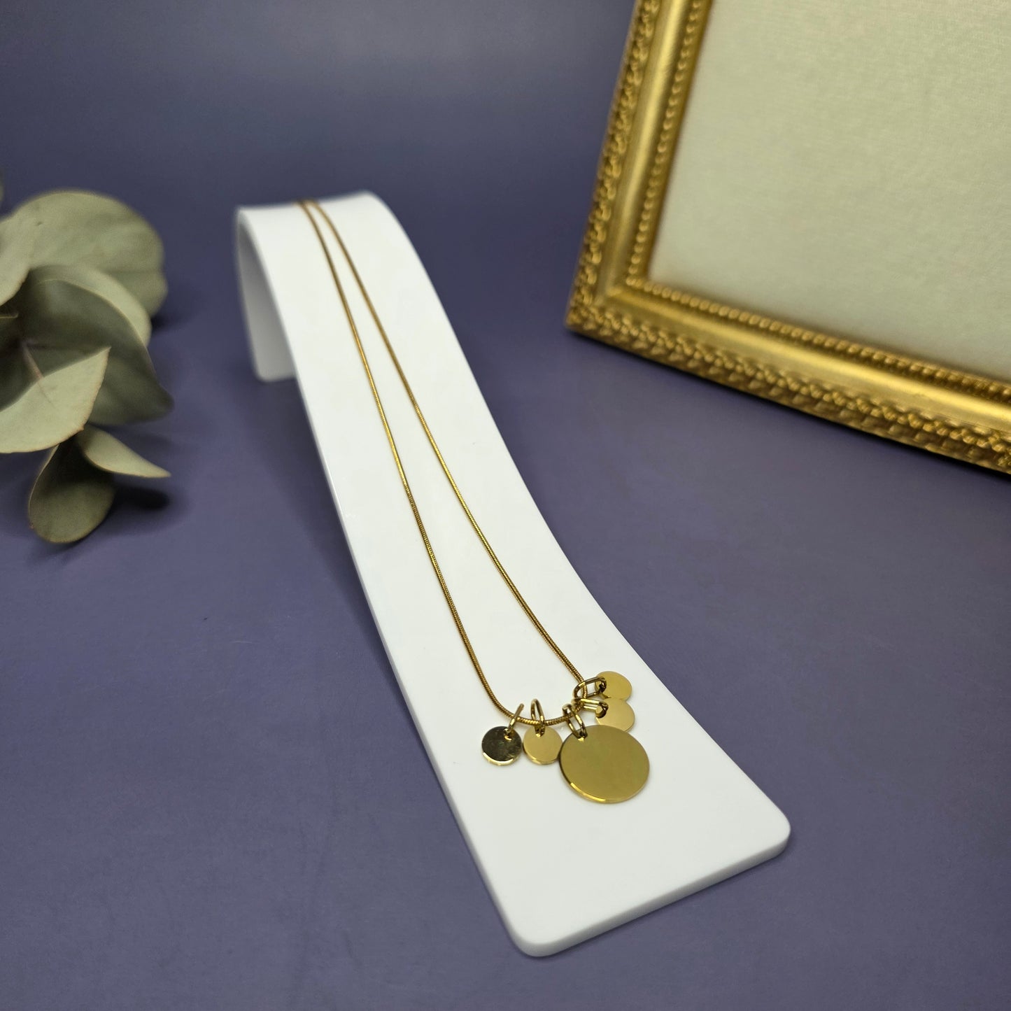 Angled view of the Golden Mamma Bear necklace on a white display stand, featuring four smaller initial pendants — My Silver Lining.