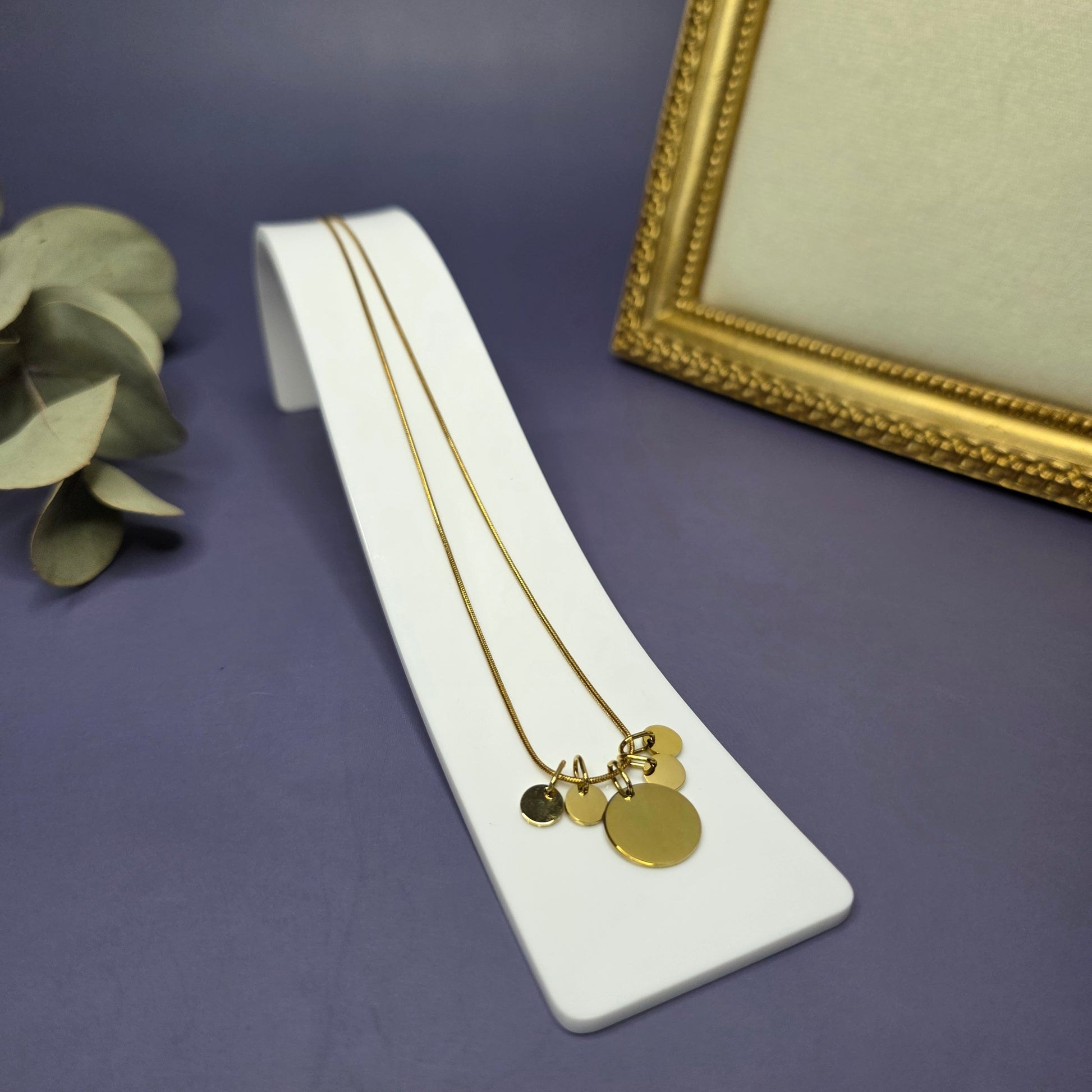 Angled view of the Golden Mamma Bear necklace on a white display stand, featuring four smaller initial pendants — My Silver Lining.