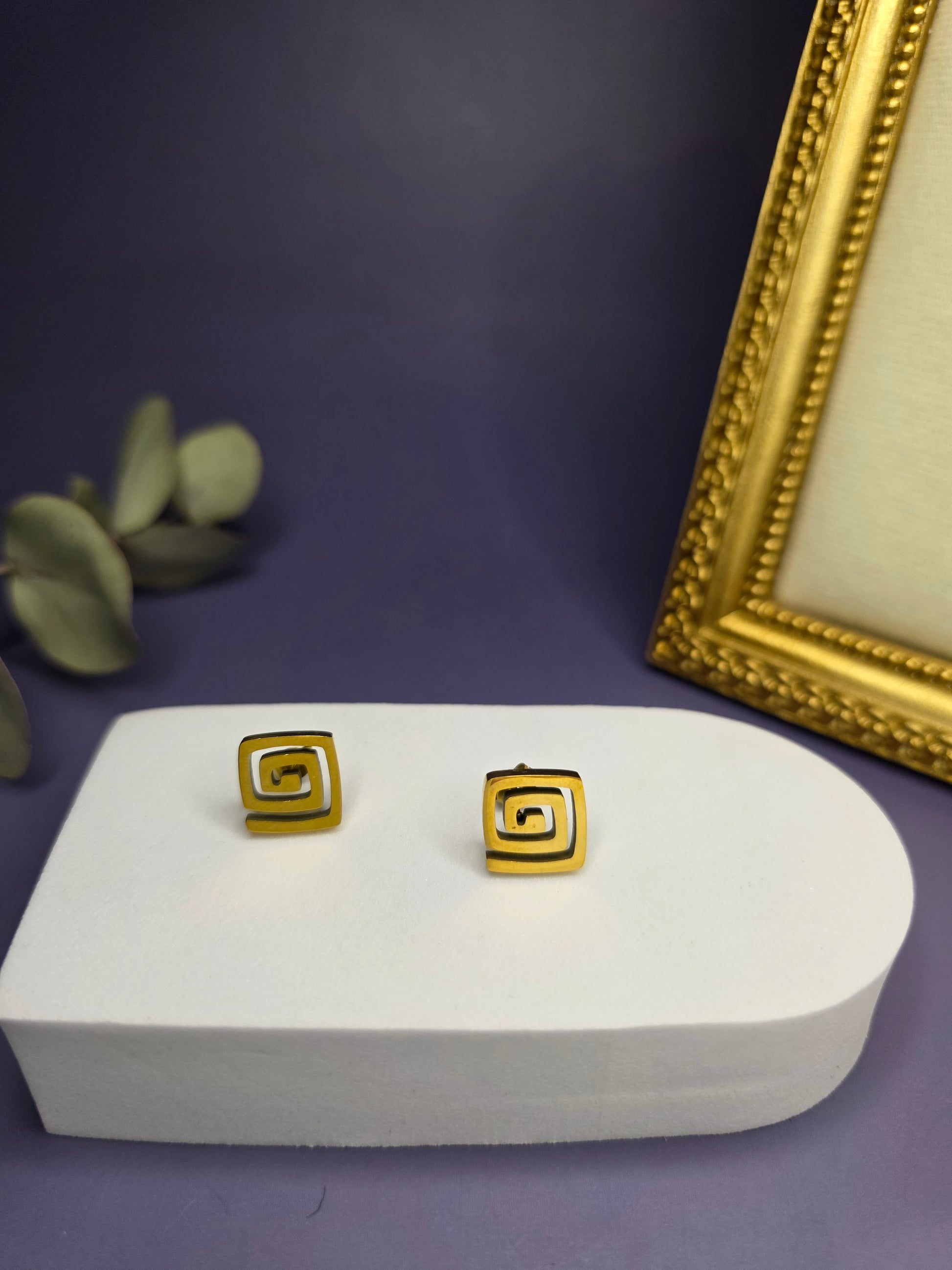 Vortex Gold Studs featuring a modern square spiral design on a white display stand. These waterproof KC gold plated earrings offer a bold and hypoallergenic jewelry choice - My Silver Lining.