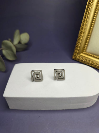Vortex Silver Studs featuring a modern square spiral design on a white display stand. These waterproof stainless steel earrings offer a sleek and hypoallergenic jewelry choice - My Silver Lining.